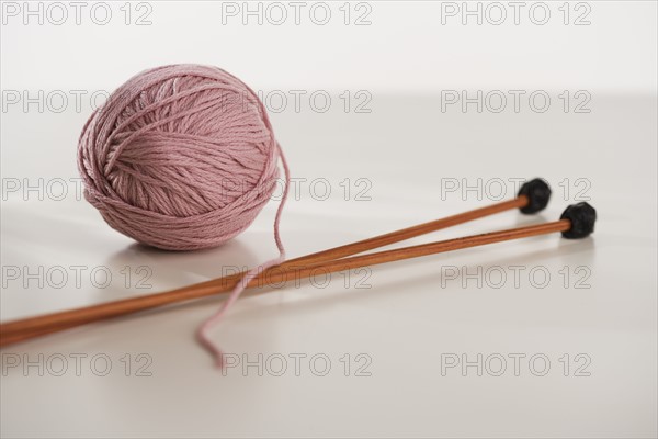 Close up studio shot of ball of yarn and knitting needles.