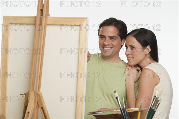 Couple smiling and looking at easel.
