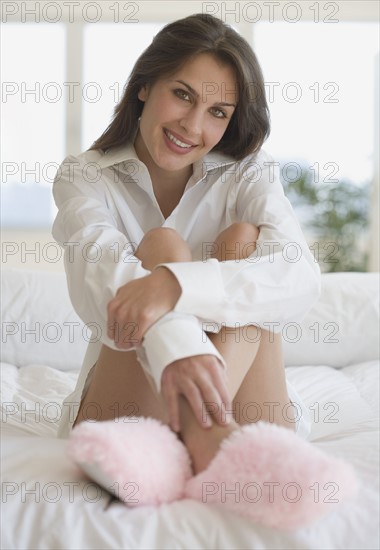 Portrait of woman wearing slippers on bed.