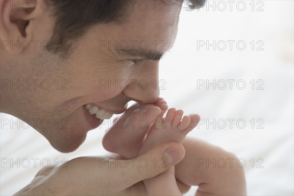 Father kissing newborn baby's feet.