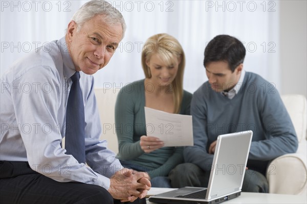 Portrait of businessman with couple in background.