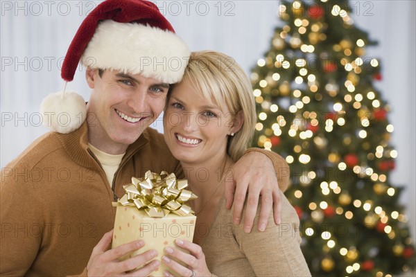 Portrait of couple holding Christmas gift.