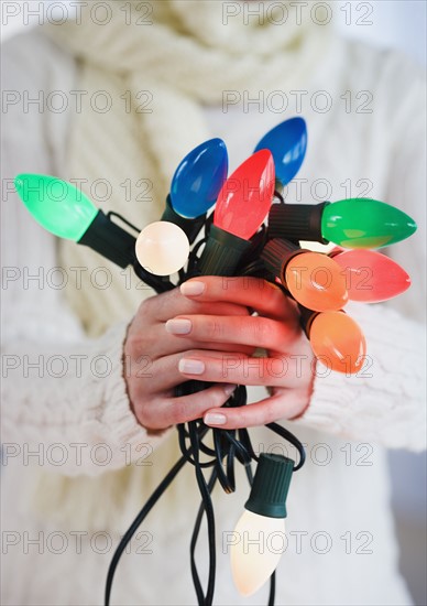 Woman holding bunch of Christmas lights.