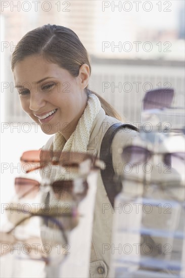 Woman looking at sunglasses in shop window.