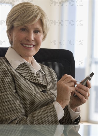 Senior businesswoman holding electronic organizer.