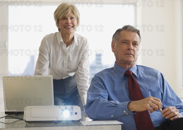 Senior businesspeople using projector in conference room.