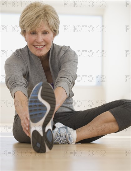 Senior woman stretching on floor.