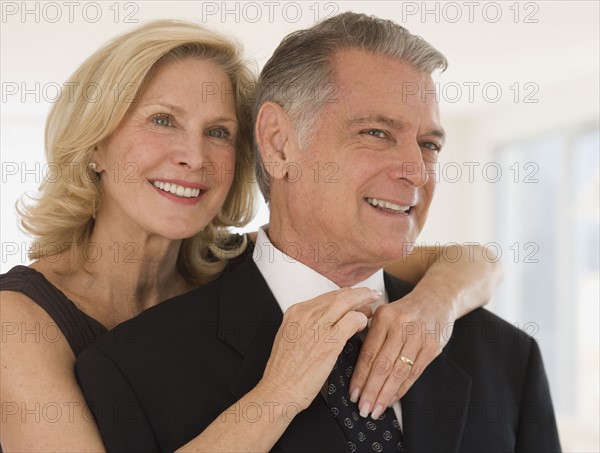 Senior woman adjusting husband's necktie.