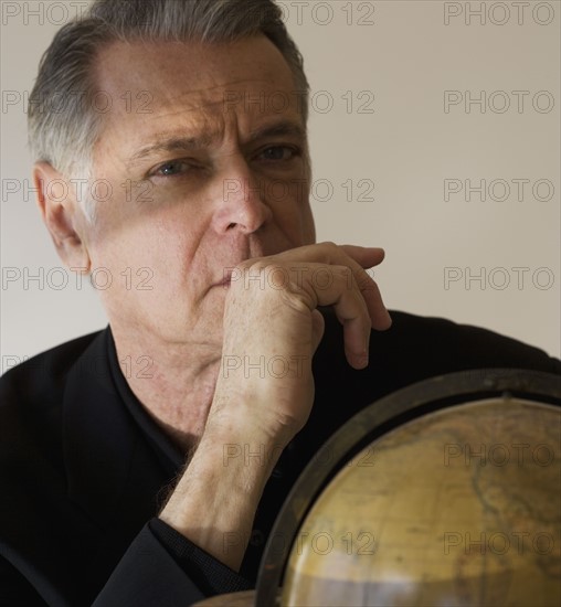 Senior businessman next to globe.