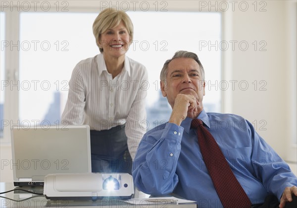 Senior businesspeople using projector in conference room.