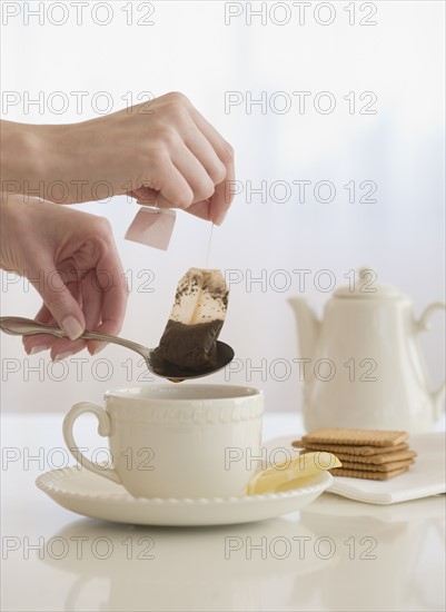 Woman taking tea bag out of cup.