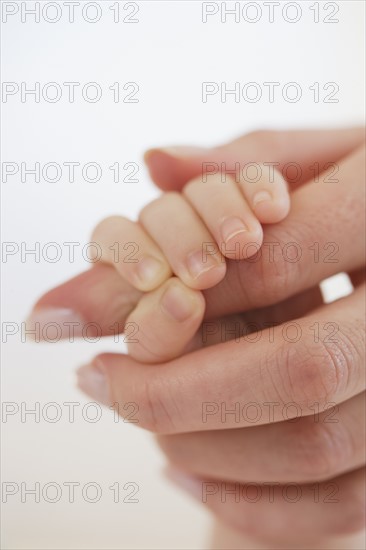 Close up of baby holding mother's hand.