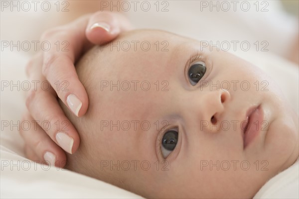 Close up of mother's hand on baby's head.