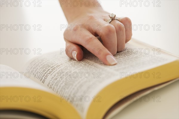 Woman's finger on page in Bible.