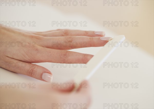 Close up of woman filing fingernails.