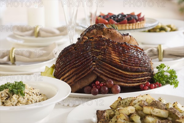 Spiral ham and side dishes on set table.