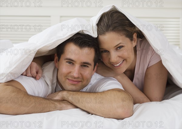 Portrait of couple under bed covers.