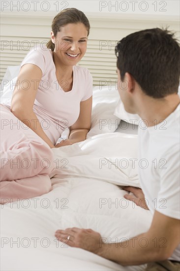 Couple smiling at each other on bed.