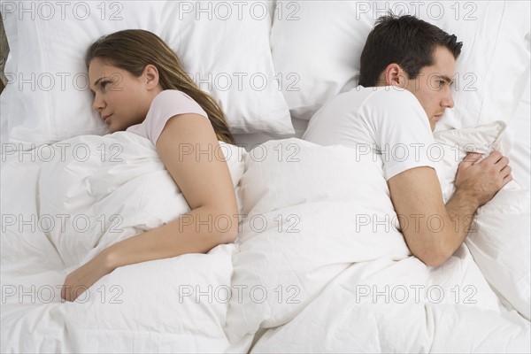 Angry couple laying in bed.