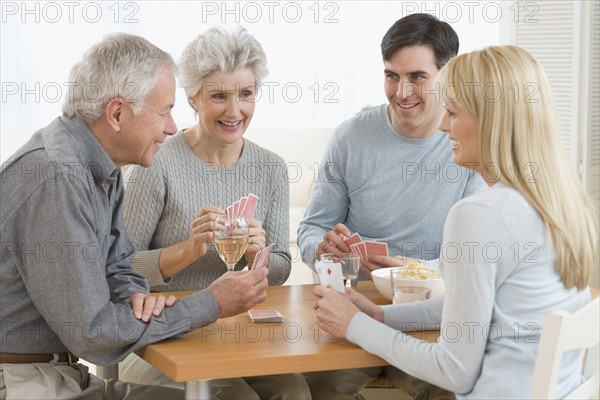 Senior couple and young couple playing cards.