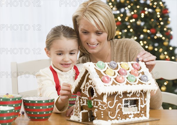 Mother and daughter making gingerbread house.