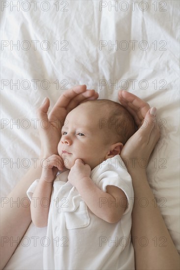 Mother holding hands around newborn baby's head.