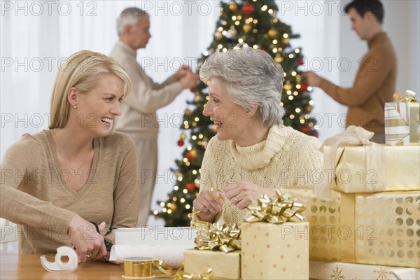 Mother and adult daughter wrapping Christmas gifts.