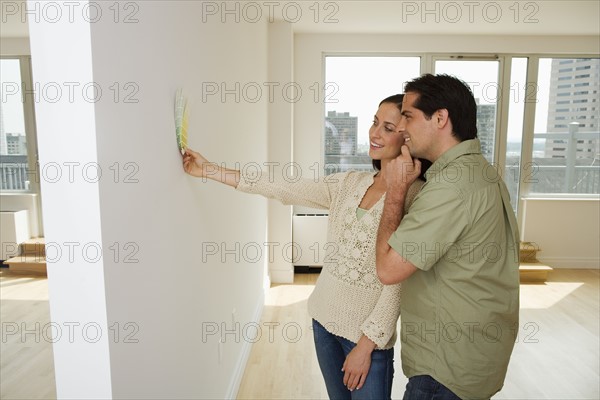 Couple holding paint swatches up to wall.