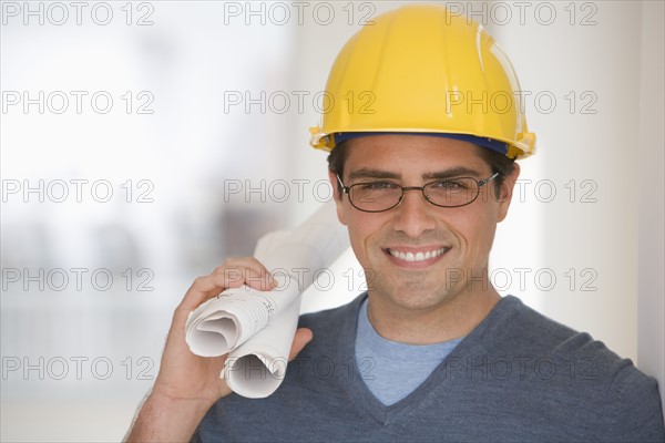 Man wearing hard hat and holding blueprints.