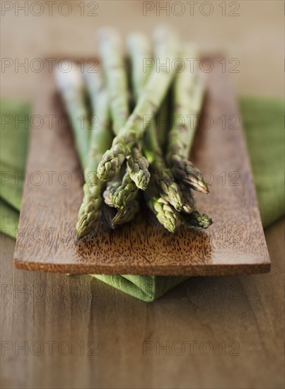 Close up of asparagus on wooden plate.