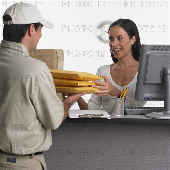 Woman behind counter receiving delivery.