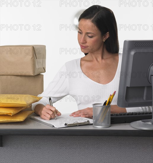 Woman logging in packages at counter.