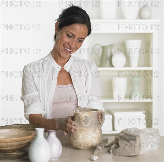 Female potter making jug.