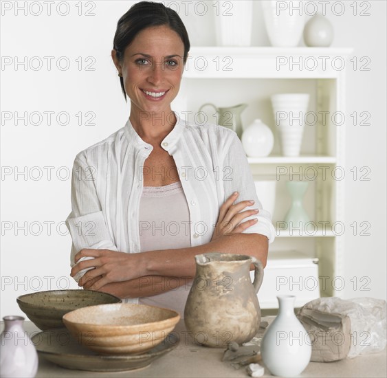Female potter smiling next to pottery.