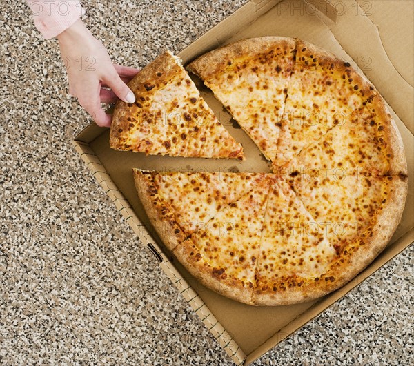 Woman taking slice of pizza from box.