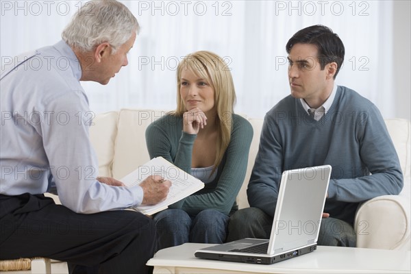 Businessman talking to couple in home.