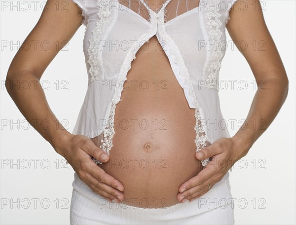 Close up of pregnant woman with hands on stomach.