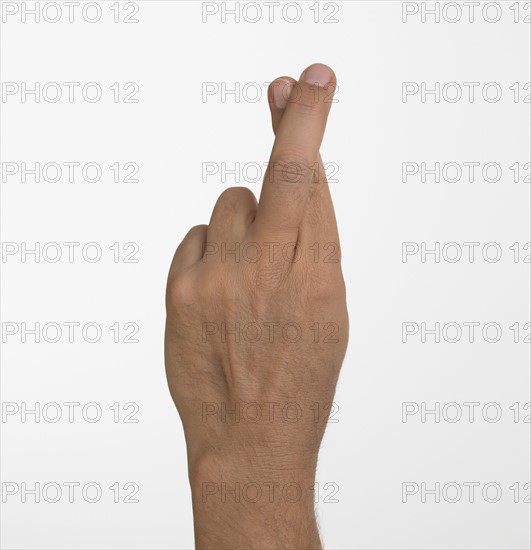 Studio shot of man's hand with fingers crossed.