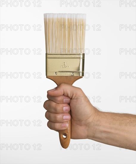 Close up studio shot of man holding paintbrush.