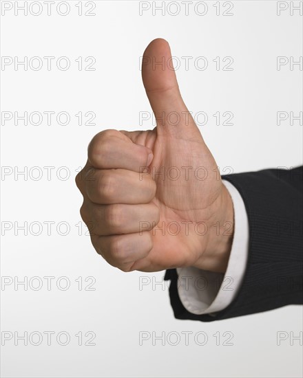 Studio shot of businessman's hand giving thumbs up.