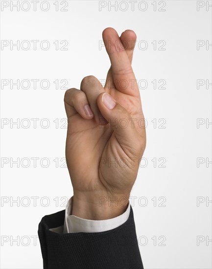 Studio shot of businessman's hand with fingers crossed.