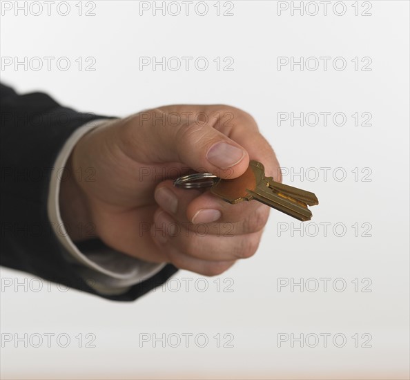 Studio shot of businessman holding keys.