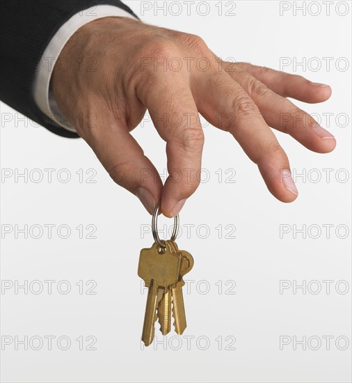 Close up studio shot of man holding set of keys.