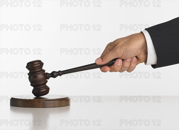 Close up studio shot of judge's hand with gavel.