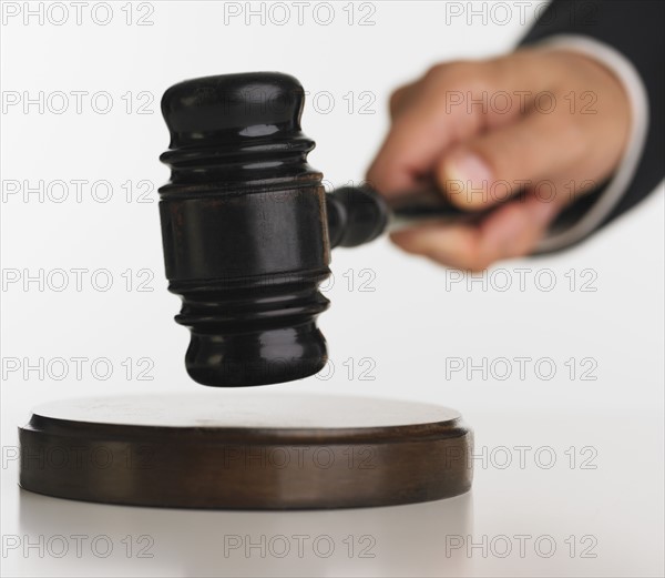 Close up studio shot of judge's hand with gavel.