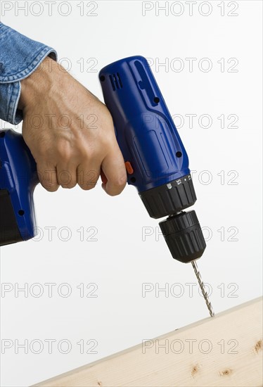 Close up of man using cordless drill.