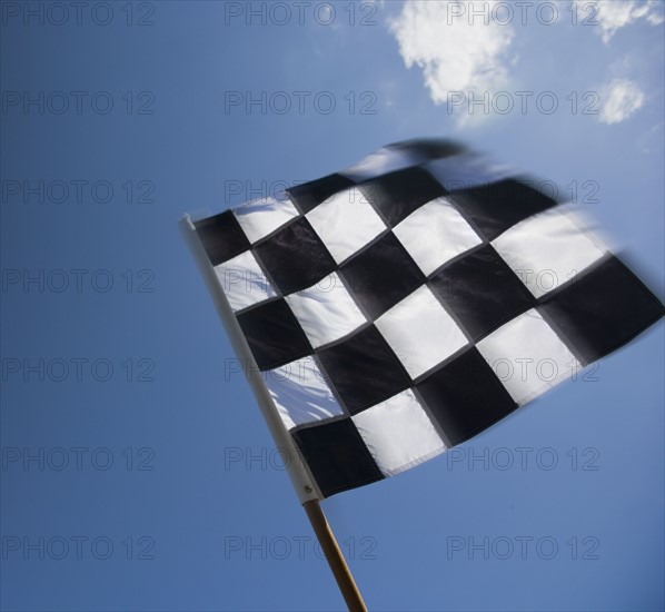 Checkered flag waving under blue sky.