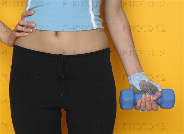 Woman in athletic gear holding dumbbell.