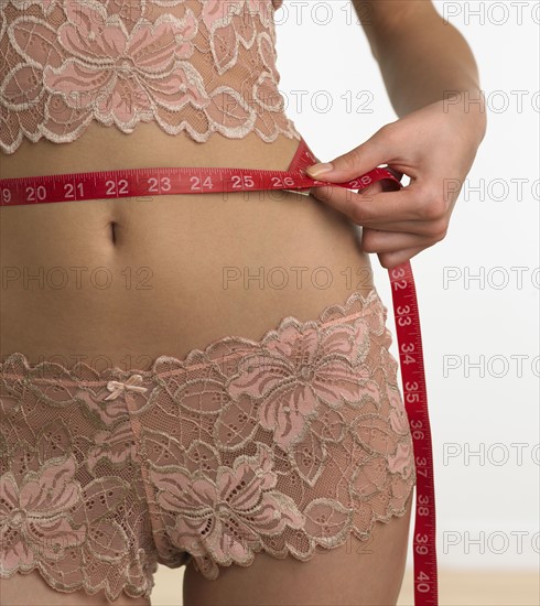 Woman in underwear measuring waist.