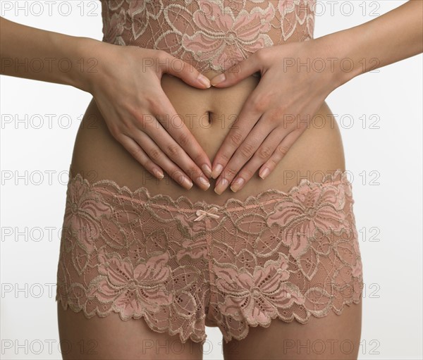 Woman in underwear making heart with hands on stomach.